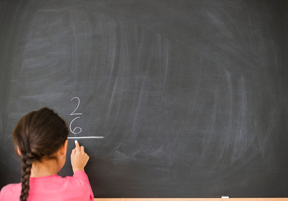 Mixed race girl doing math on blackboard, Jersey City, New Jersey, USA