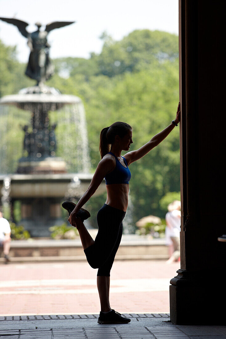 Caucasian woman stretching before exercise in park, New York City, New York, USA