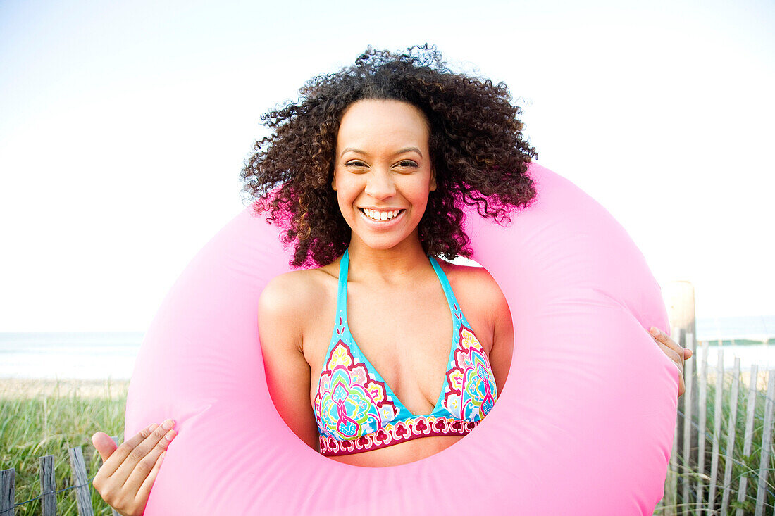 Smiling Hispanic woman holding inflatable ring, Hull, Massachusetts, United States