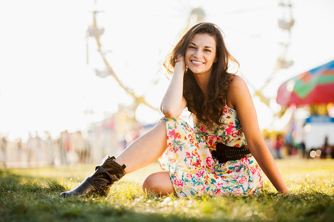 Caucasian woman sitting in grass at carnival, Salt Lake City, Utah, USA