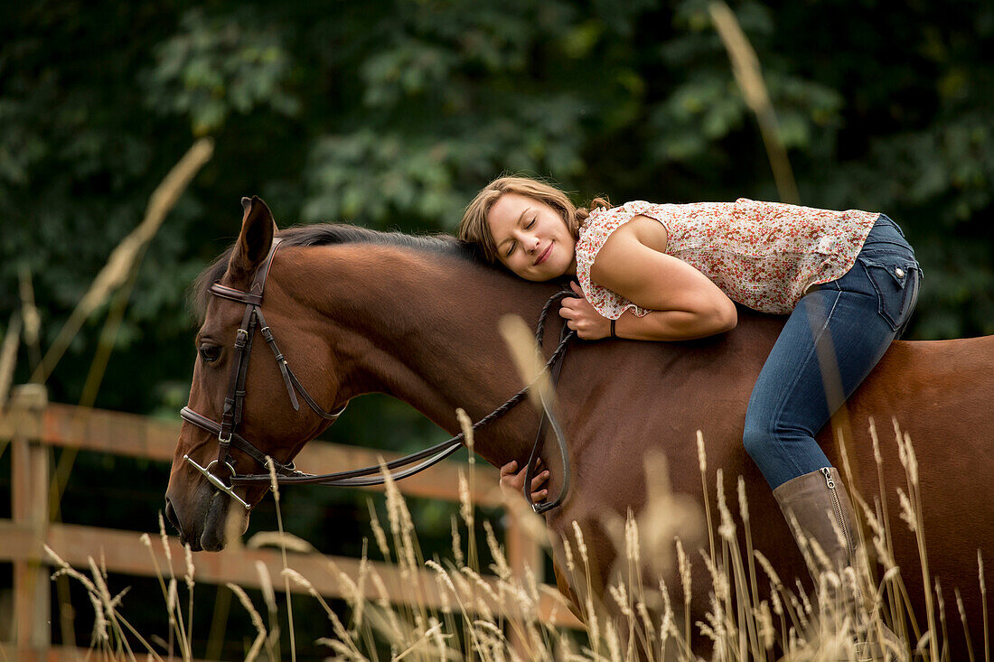 Caucasian woman laying on horse in pen, Seattle, WA, USA