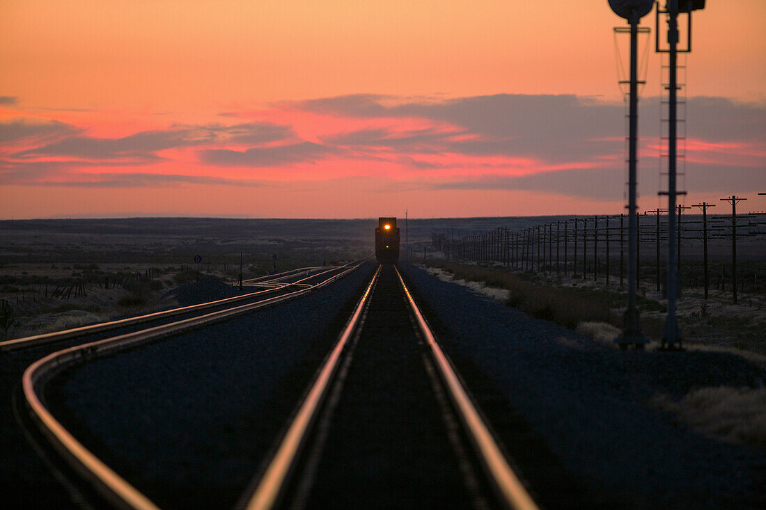 Sunset over train on tracks in rural landscape, Mountain Home, ID, USA