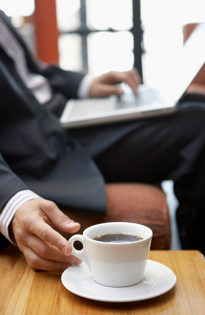 Businessman reaching for cup of coffee, Vancouver, Canada