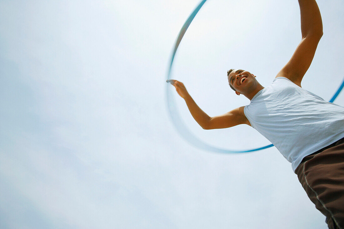 Hispanic man playing with hula hoop, Cape Cod, MA