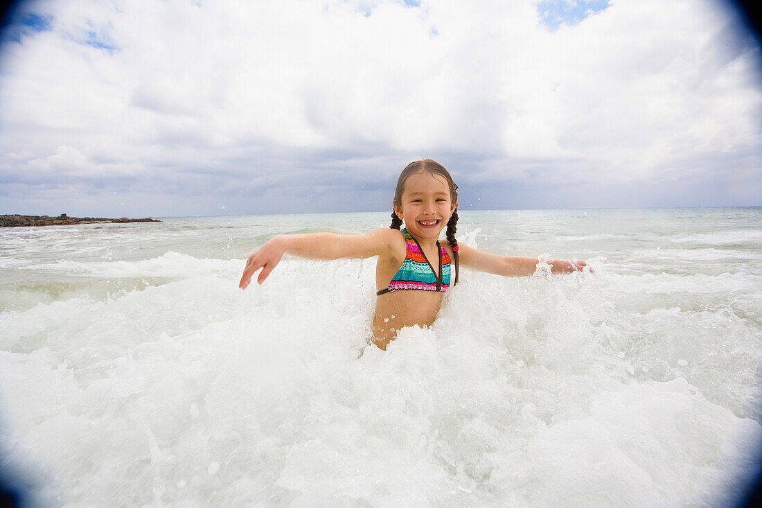 Asian girl playing in surf, Kauai, HI