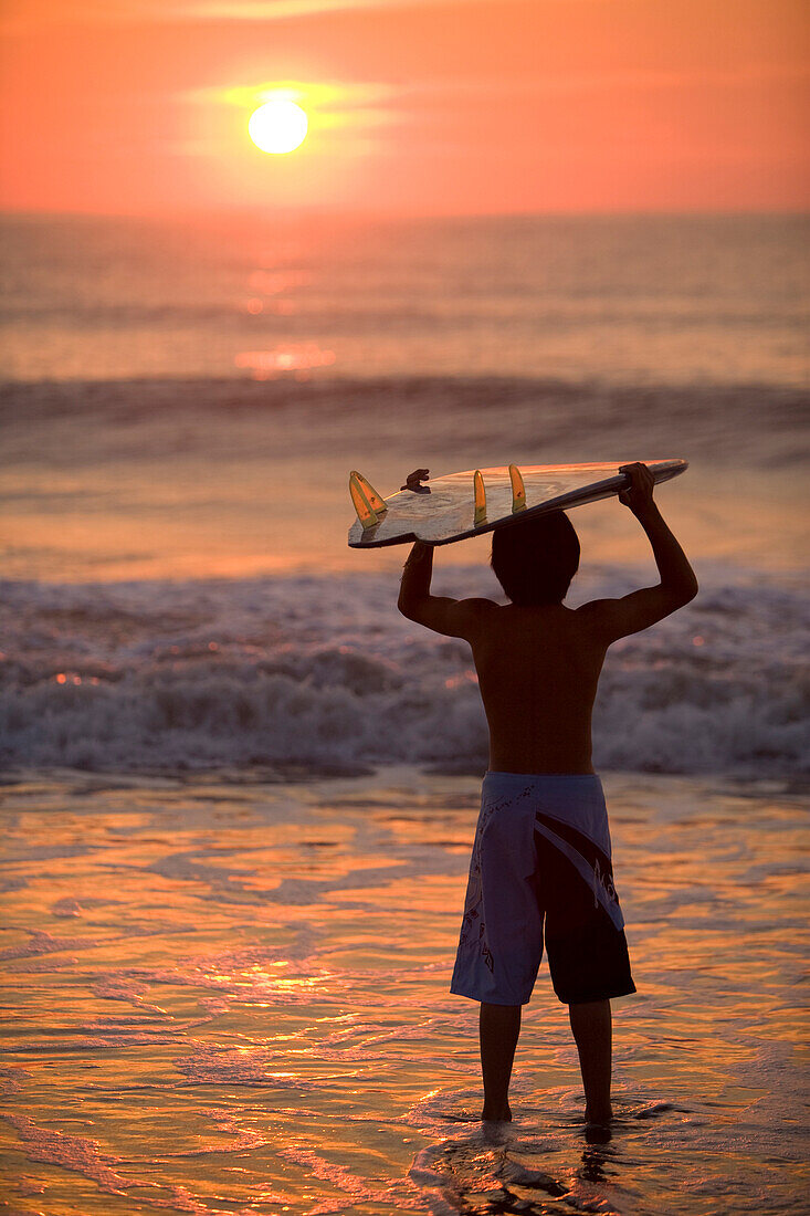Asian boy holding surfboard at beach, Virginia Beach, VA