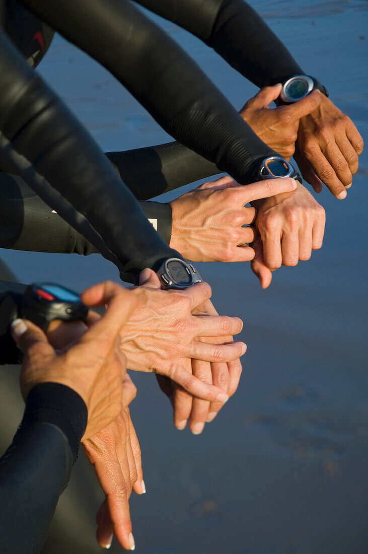 Multi-ethnic swimmers checking watches, Newport Beach, CA