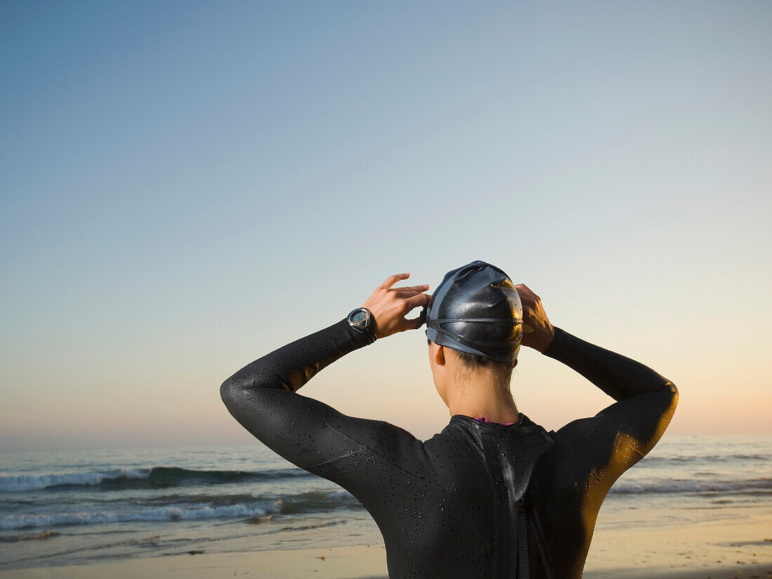 Rear view of Hispanic woman wearing wetsuit, Newport Beach, CA