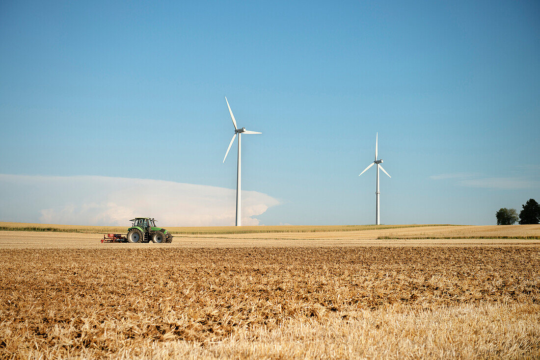 Tractor in field, wind wheels in background, Merklingen, Baden-Wuerttemberg, Germany