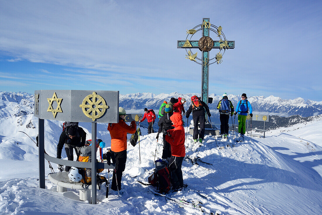Skitourengeher an einem Gipfelkreuz mit Zeichen der Weltreligionen, Kleiner Gilfert, Tuxer Alpen, Tirol, Österreich