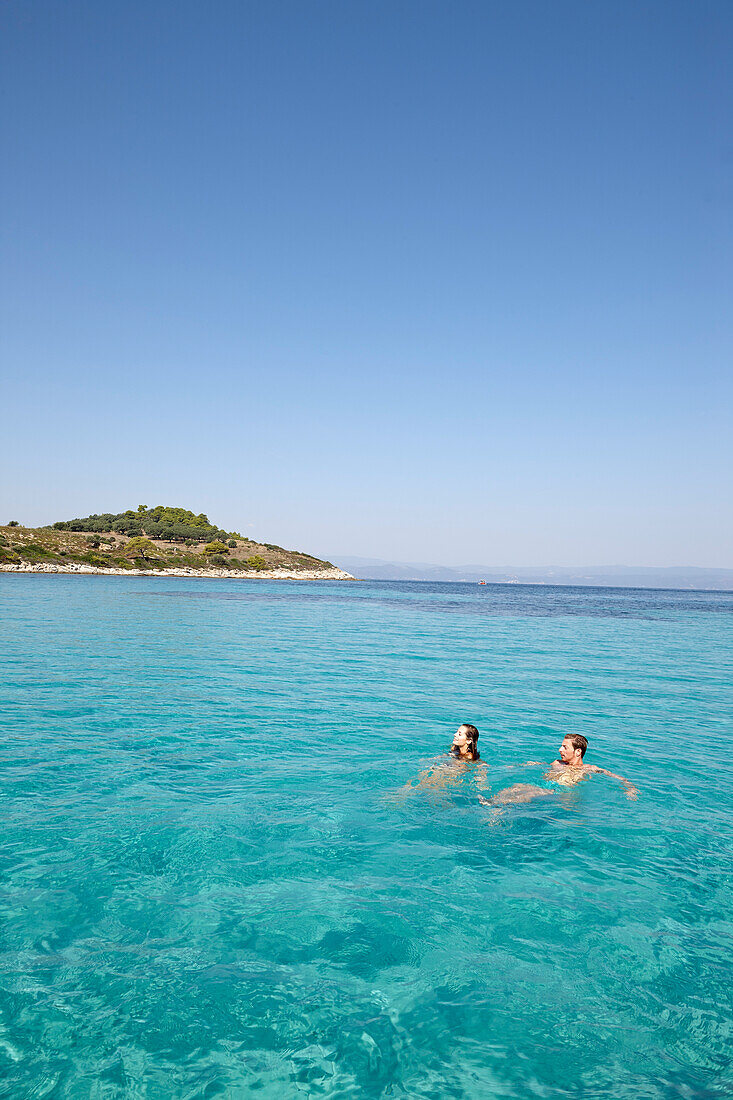 Couple swimming in Blue Lagoon, Vourvourou, Sithonia, Chalkidiki, Greece