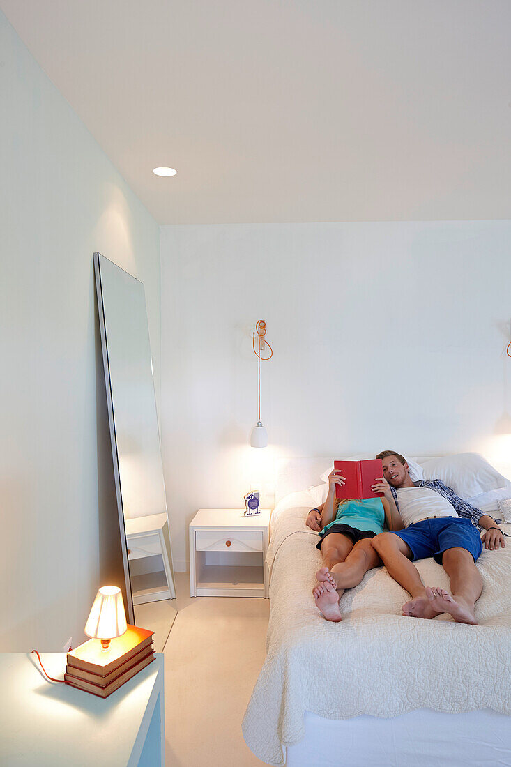 Couple lying on a hotel bed while reading a book, Sithonia, Chalkidiki, Greece