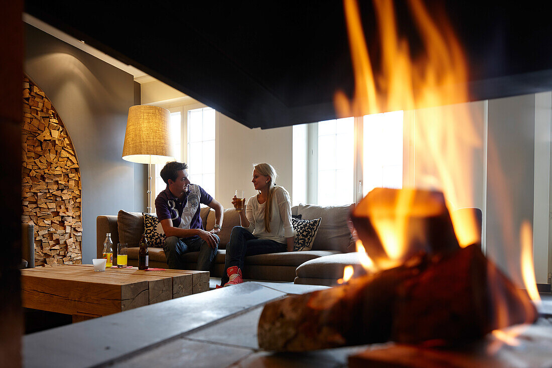 Couple sitting in a hotel lounge with a fireplace, Adelboden, Canton of Bern, Switzerland