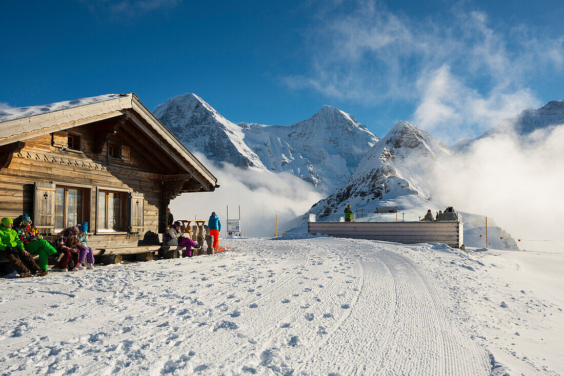 Timber hut in Winter on Maennlichen mountain with Eiger Moench and Jungfrau in the background, Grindelwald, canton of Bern, Switzerland
