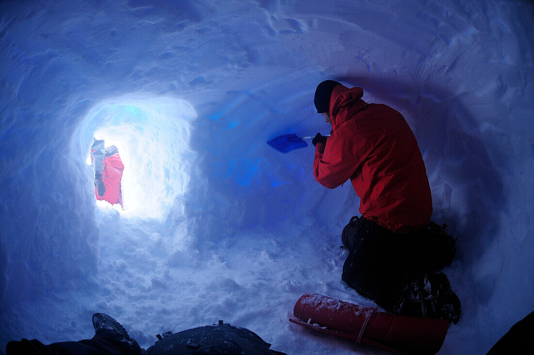 Mountaineer digging a snow cave at Collado Este, Monte Sarmiento, Cordillera Darwin, Tierra del Fuego, Chile