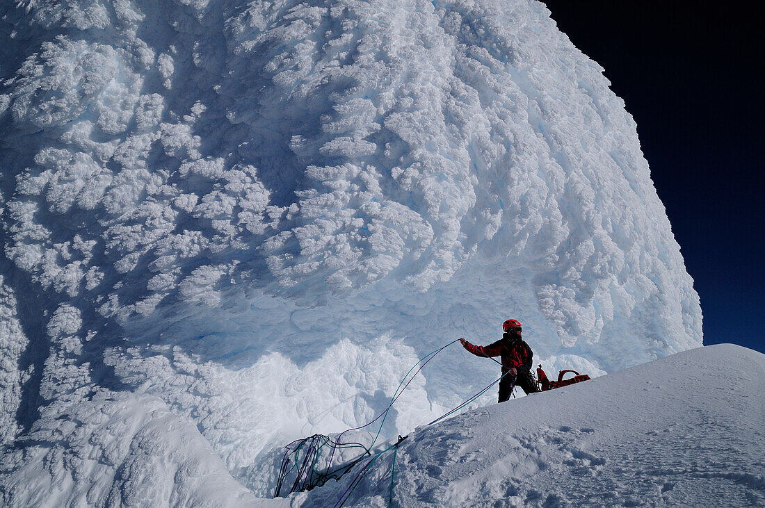 Mountaineer below an ice mushroom in the north face of Monte Sarmiento, Cordillera Darwin, Tierra del Fuego, Chile