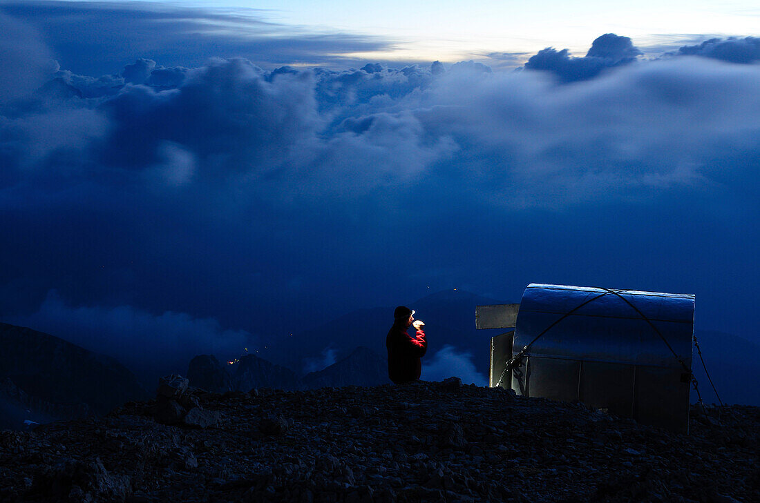 Climber with headlamp beside wilderness hut bivacco Ettore Castiglioni, Crozzon di Brenta, Brenta Dolomites, Trentino, Italia