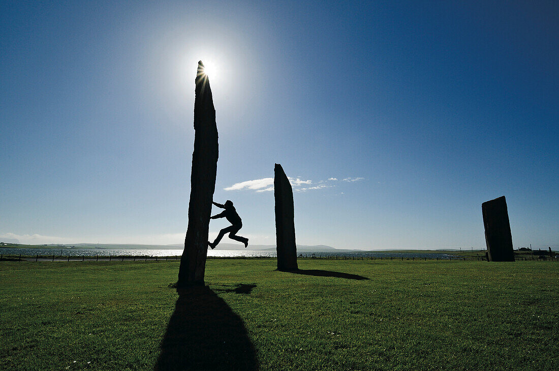 Mann klettert an einem Stein, Stones of Stenness, Mainland, Orkneyinseln, Schottland, Großbritannien