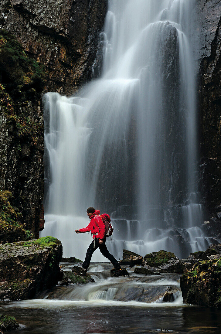 Wanderer, Wasserfall im Hintergrund, Highlands, Schottland, Großbritannien