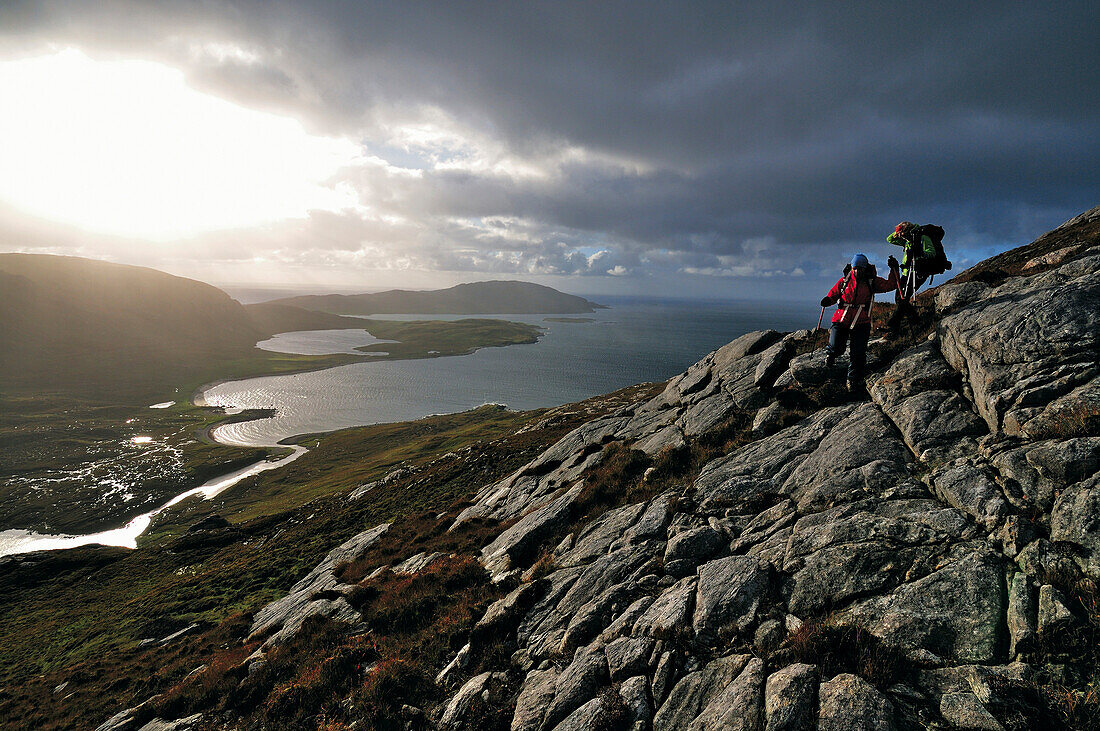 Hikers descending from Taran Mor to Loch Crabhadail, Harris, Lewis and Harris, Outer Hebrides, Scotland, Great Britain