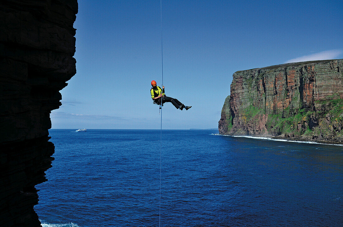 Climber abseiling from the top of the Old Man of Hoy, Orkney Islands, Scotland, Great Britain