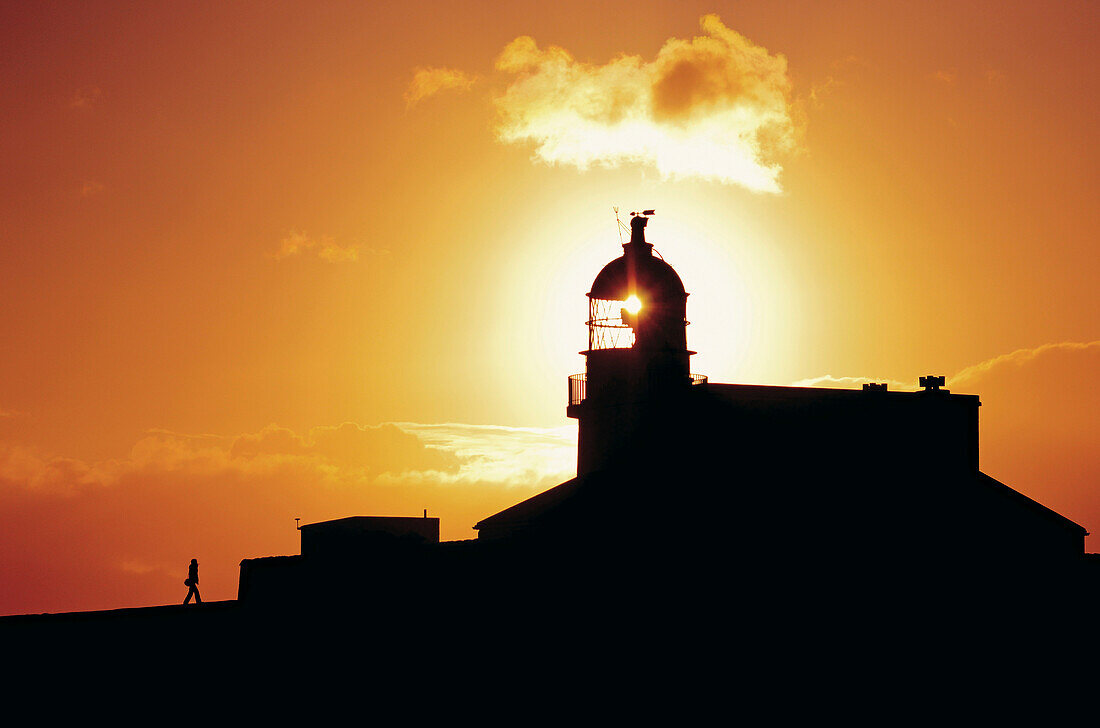 Mann im Sonnenuntergang beim Stoer Head Leuchtturm, Stoer, Highlands, Großbritannien
