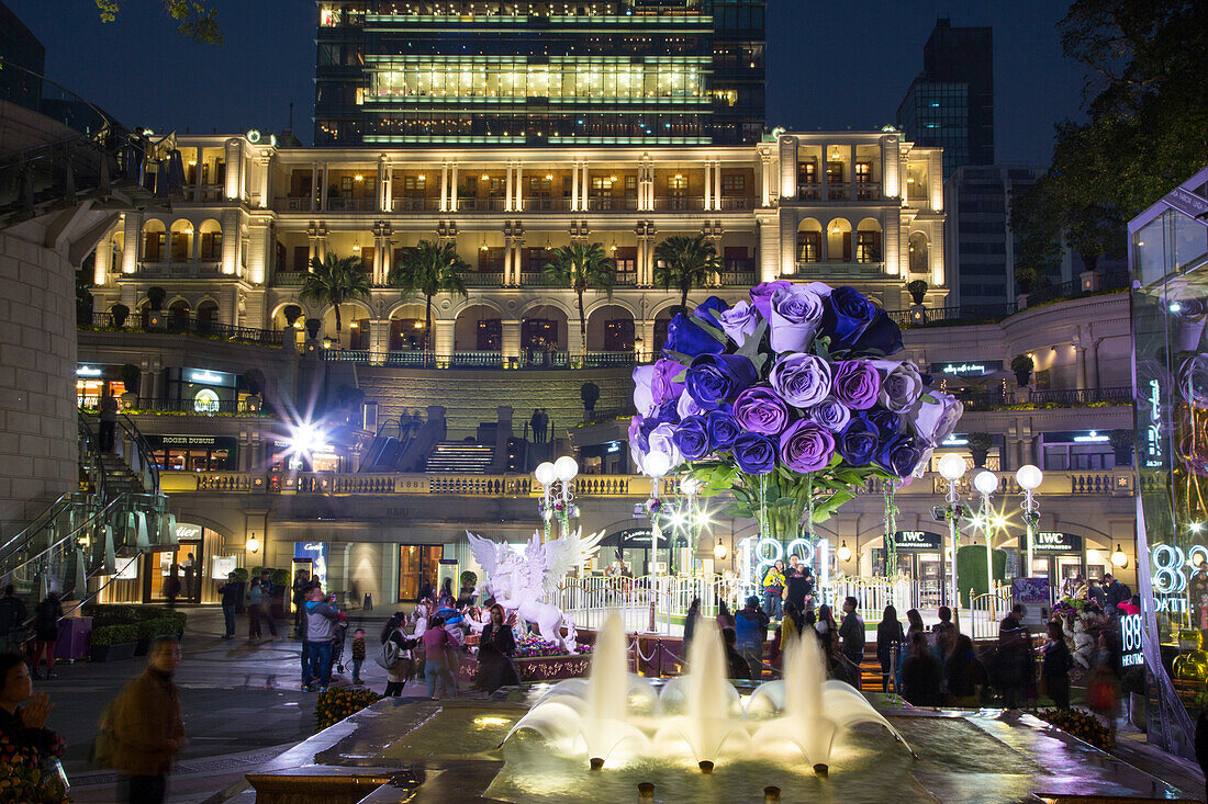 Fountain and giant flower bouqet decoration outside 1881 Heritage shopping complex at night, Tsim Sha Tsui, Kowloon, Hong Kong