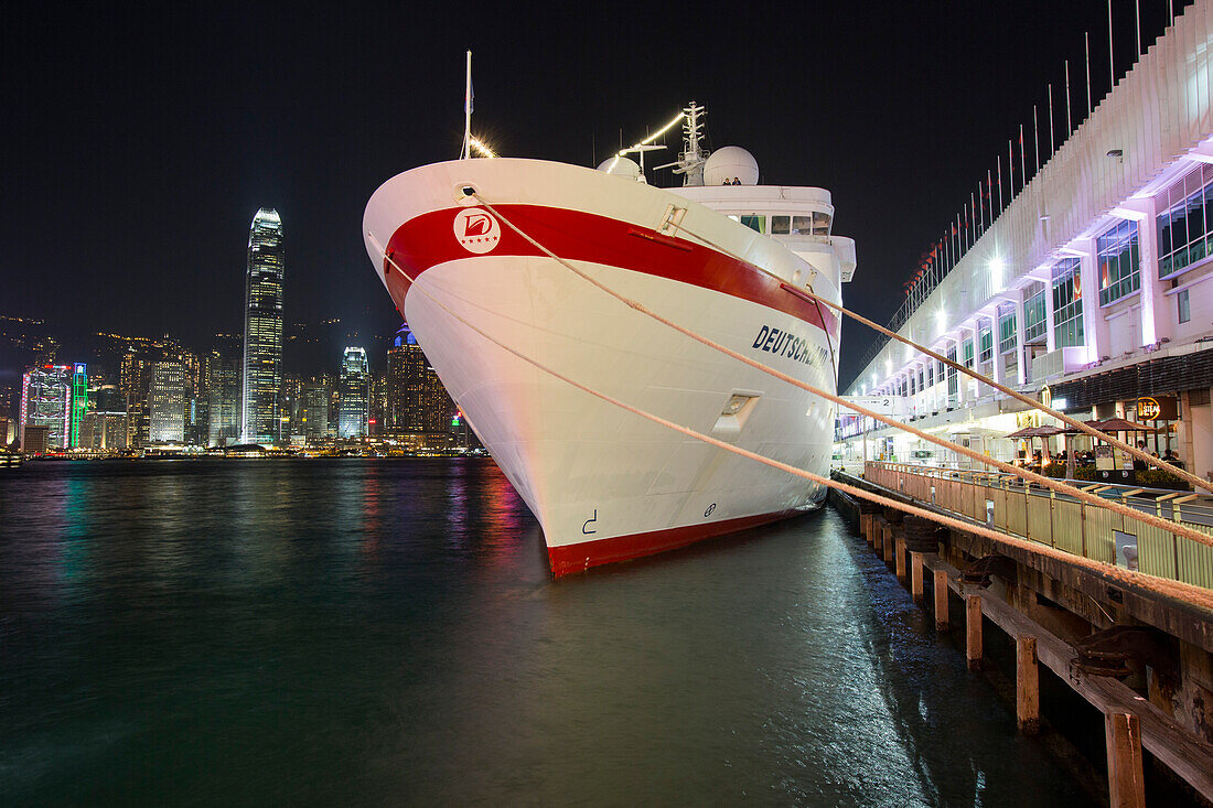 Cruise ship MS Deutschland, Reederei Peter Deilmann, at Ocean Terminal with skyline across Hong Kong Harbour at night, Tsim Sha Tsui, Kowloon, Hong Kong