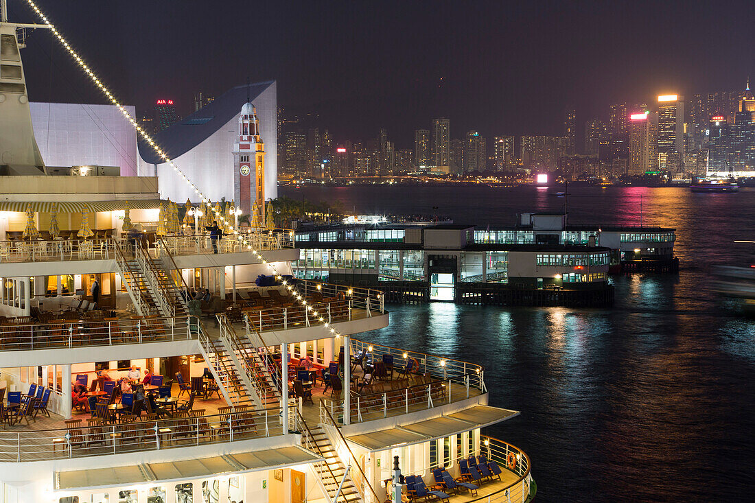 Cruise ship MS Deutschland, Reederei Peter Deilmann, at Ocean Terminal with skyline across Hong Kong Harbour at night, Tsim Sha Tsui, Kowloon, Hong Kong
