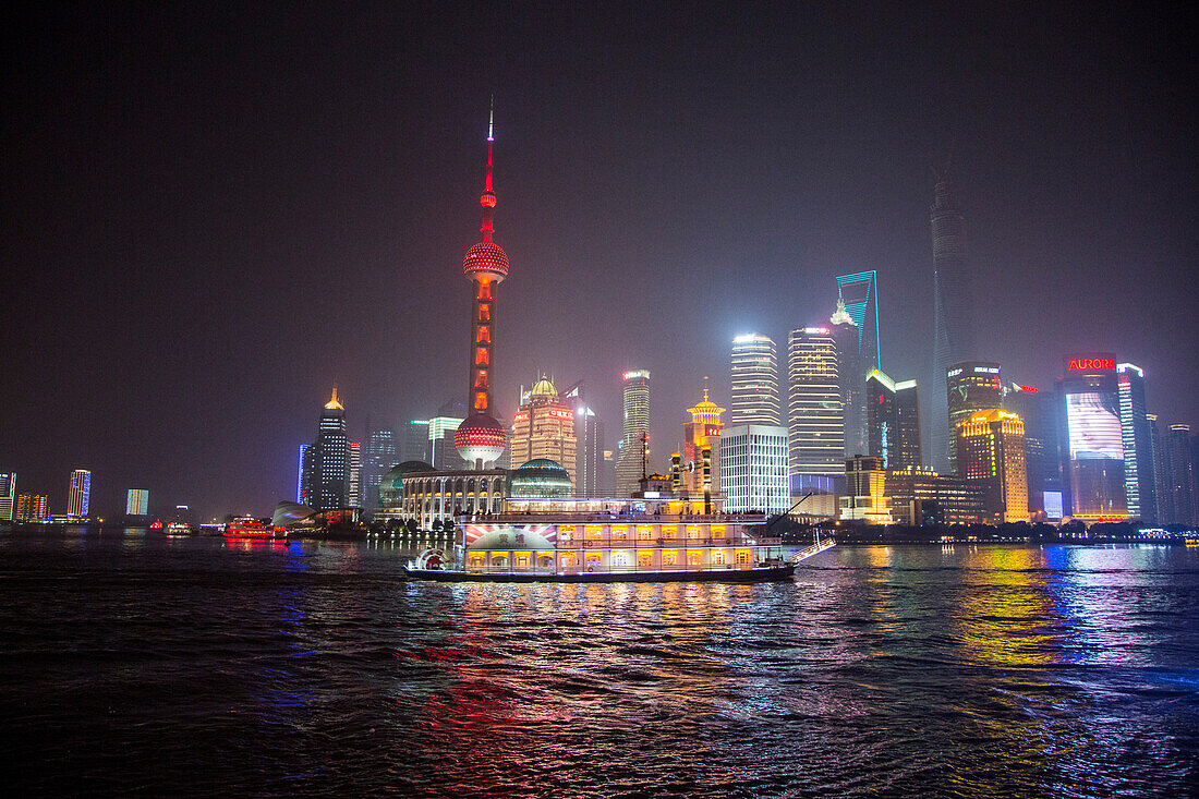 Ausflugsboot auf dem Huangpu Fluss mit Oriental Pearl Tower und Pudong Skyline bei Nacht, Shanghai, China