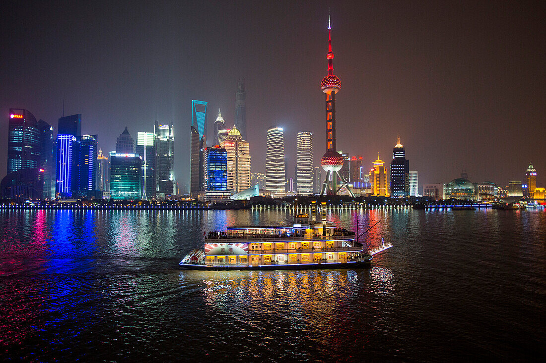 Ausflugsboot auf dem Huangpu Fluss mit Oriental Pearl Tower und Pudong Skyline bei Nacht, Shanghai, China