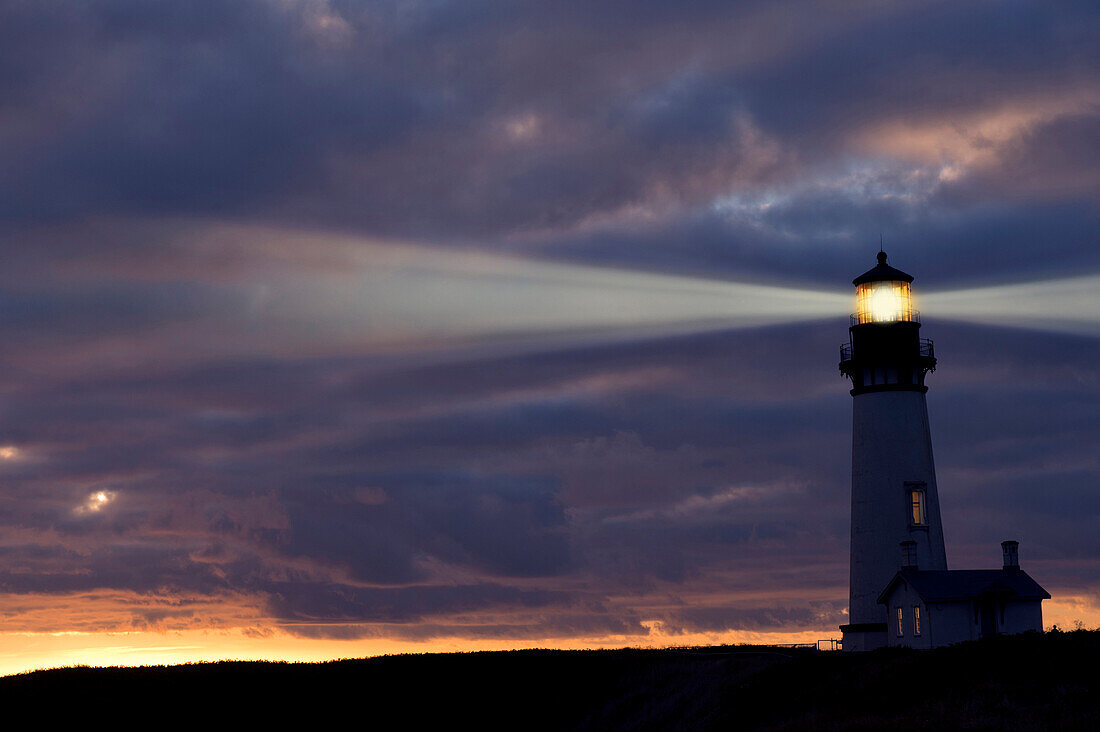 Lighthouse shining against cloudy sky, Newport, OR, USA
