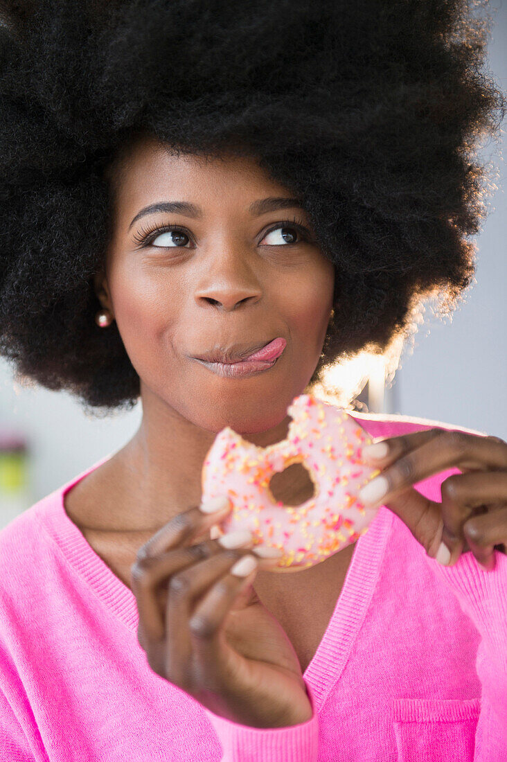 Mixed race woman eating donut, Jersey City, New Jersey, USA