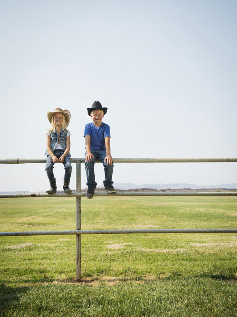 Caucasian children sitting on fence on farm, Saint George, Utah, USA