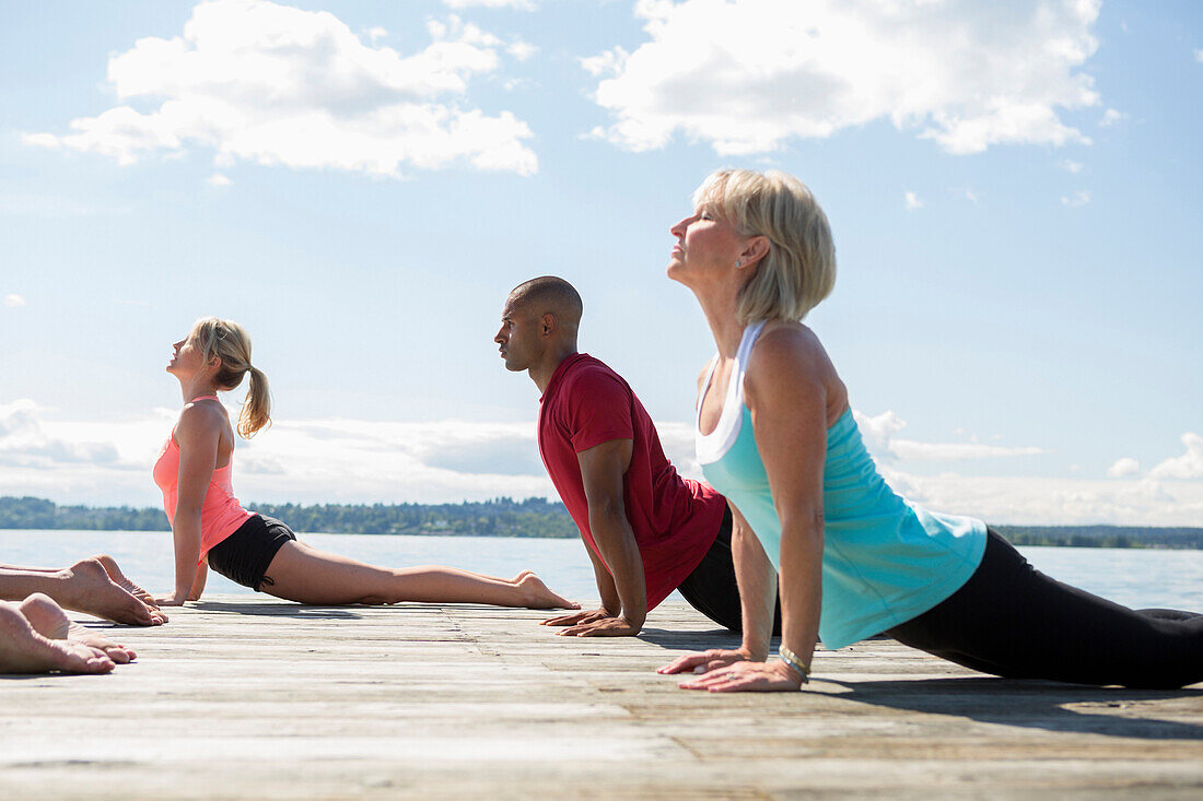 Weiße Menschen üben Yoga auf einem hölzernen Steg, Seattle, WA, USA