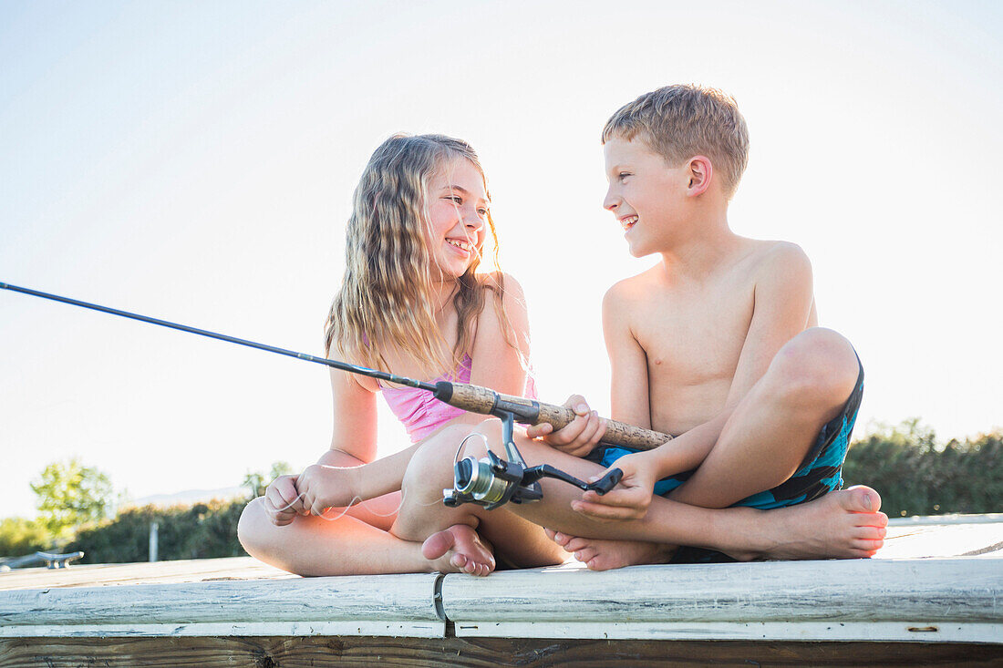 Caucasian children fishing off dock, American Fork, Utah, USA