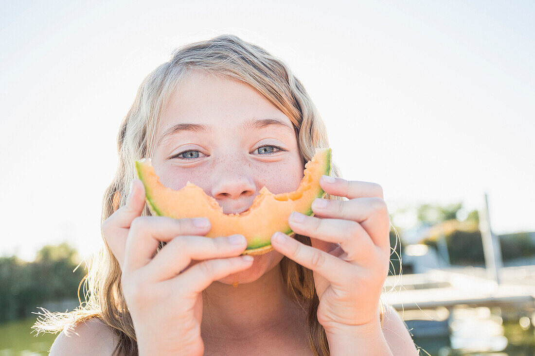 Caucasian girl eating cantaloupe slice, American Fork, Utah, USA