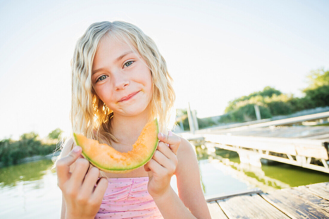 Caucasian girl eating cantaloupe slice, American Fork, Utah, USA