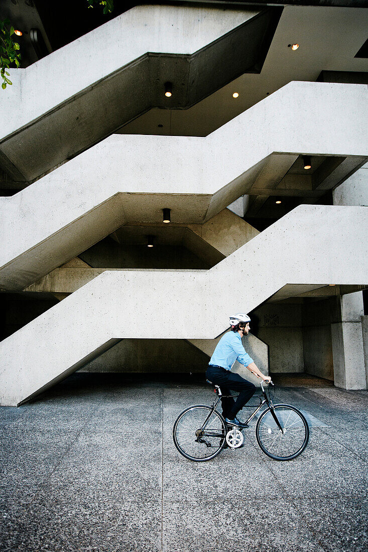 Caucasian businessman riding bicycle outside office building, Los Angeles, California, USA