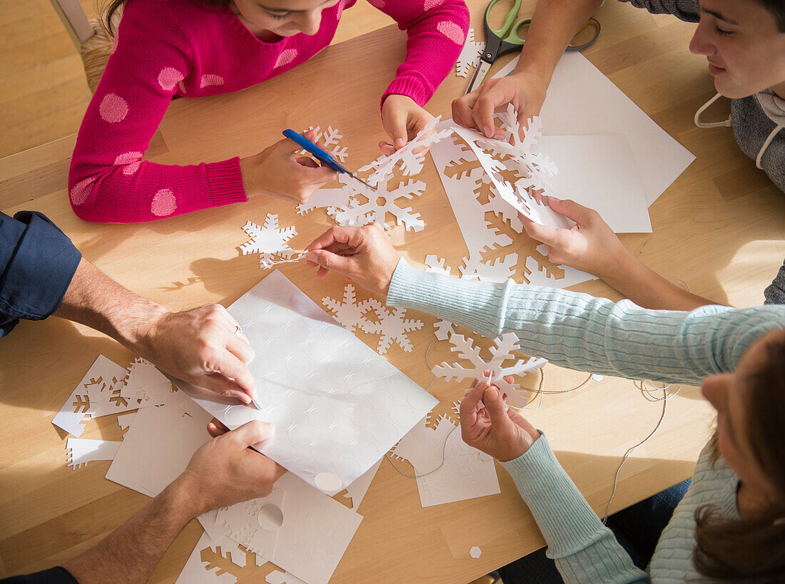 Caucasian family cutting out paper snowflakes, Jersey City, New Jersey, USA