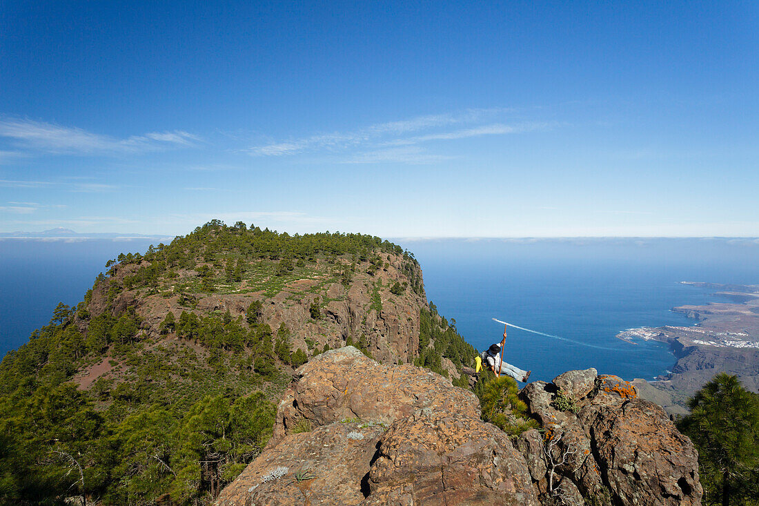 Wanderer mit Hirtenstab, Blick vom Berg Faneque auf Puerto de las Nieves und Agaete, Gebirge, Naturschutzgebiet, Naturpark Tamadaba, UNESCO Biosphärenreservat, Westküste, Gran Canaria, Atlantik, Kanarische Inseln, Spanien, Europa