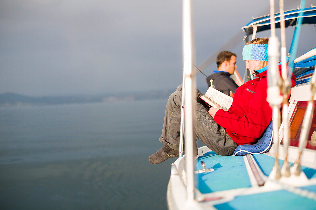 Woman reading on the deck of a sailing boat, Gulf of Trieste, Gorizia, Friuli Venezia Giulia, Italy