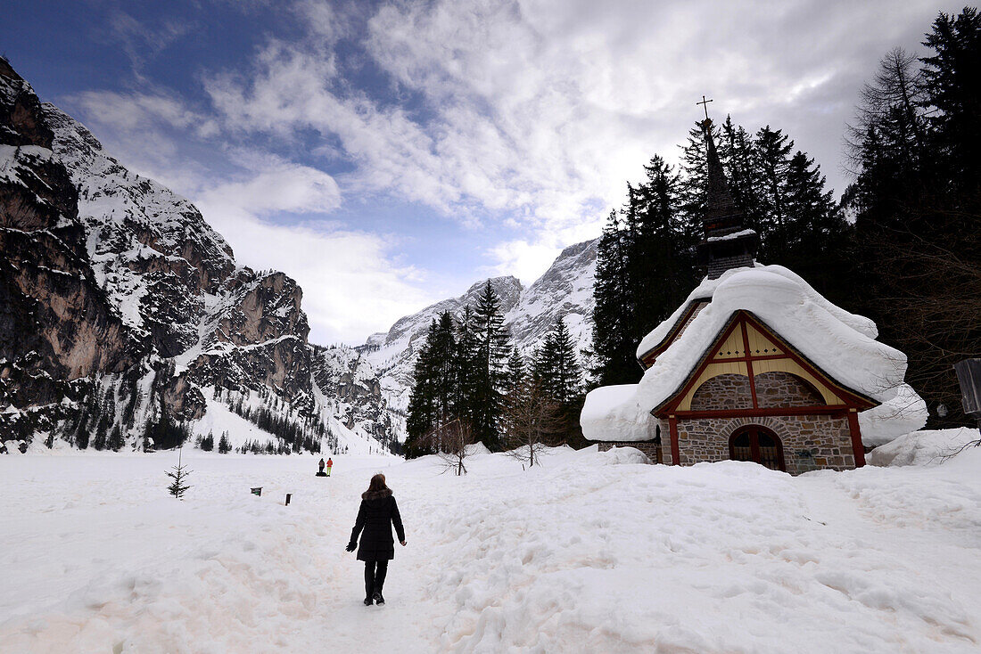 Person hiking at lake Lago di Braies, Puster valley in winter, South Tyrol, Italy