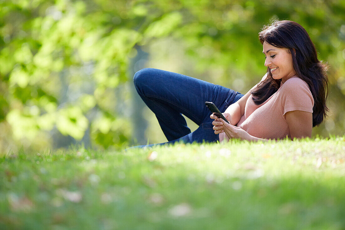 35 Jahre alte Frau mit Smartphone im Park. Donostia. San Sebastian. Gipuzkoa. Baskenland, Spanien.