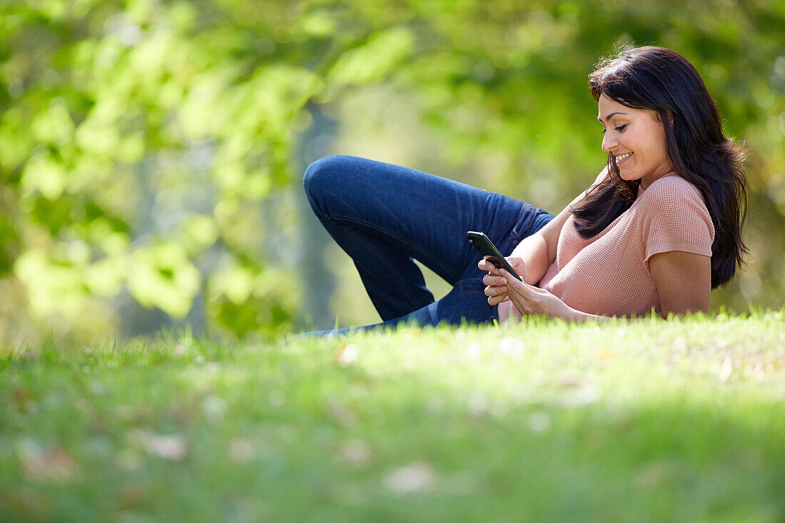 35 year old woman with smartphone in park. Donostia. San Sebastian. Gipuzkoa. Basque Country, Spain.