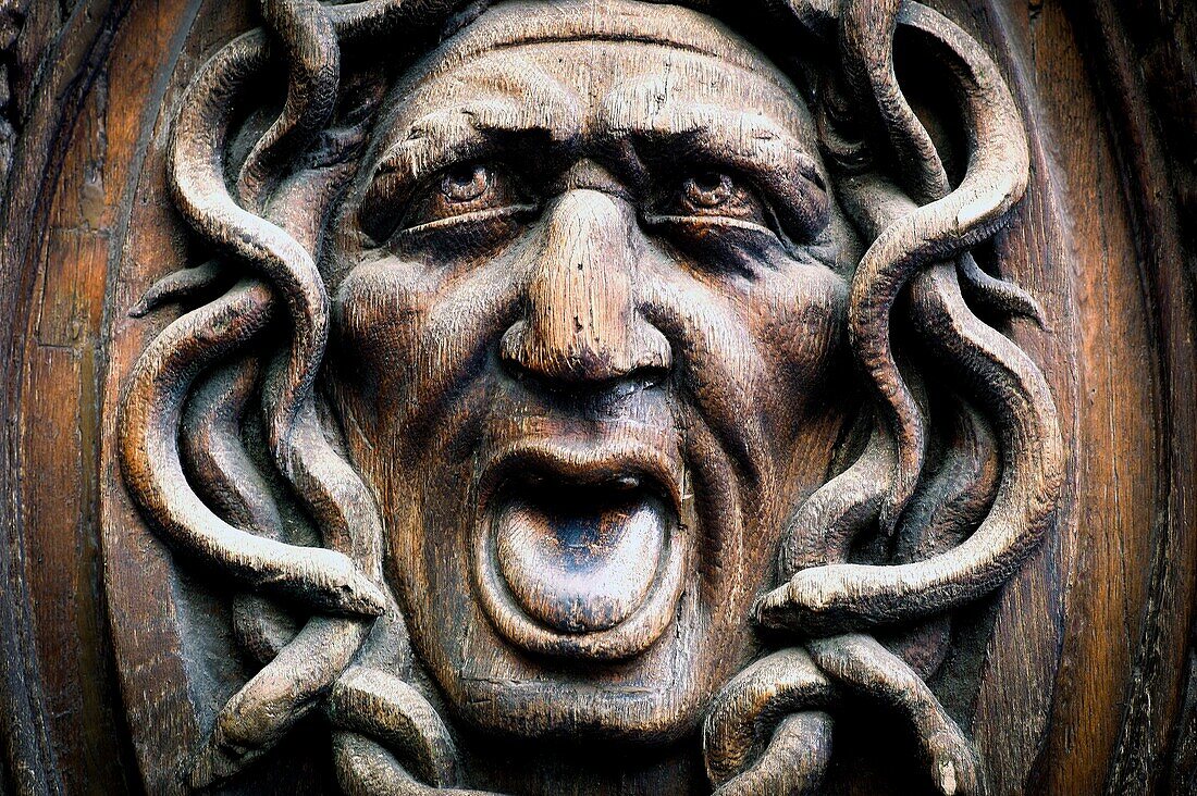 Close up of a face carved on a wooden door in the Marais, Paris, France