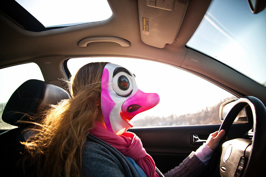 Woman driving car wearing clown mask