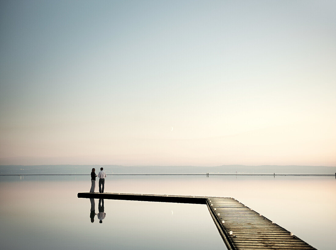 Mature couple standing on jetty overlooking lake