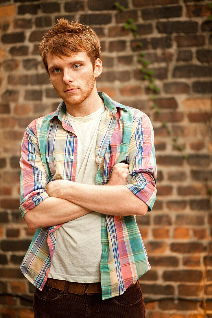 Portrait of young man in front of brick wall