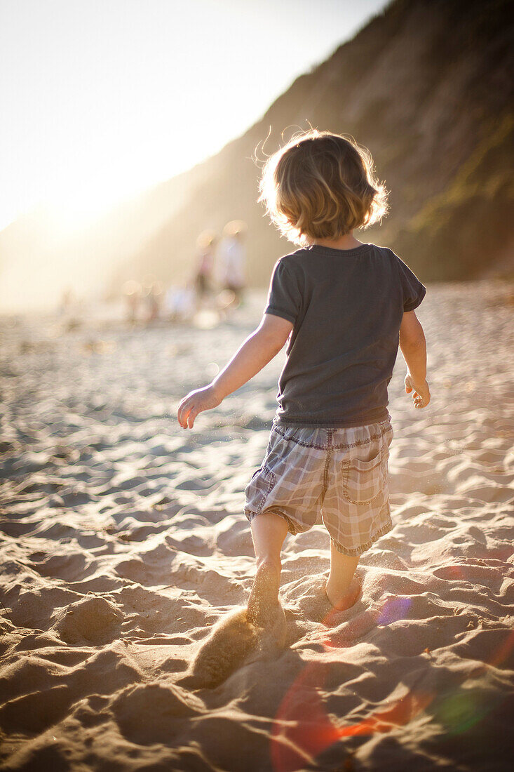 Little boy on sandy beach at sunset